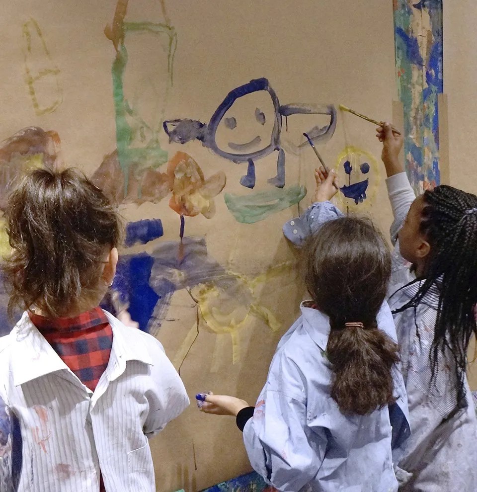 Kinder malen gemeinsam an einer grossen Pappwand